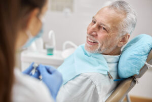 Edlerly man watching his dentist prepare for dental treatment