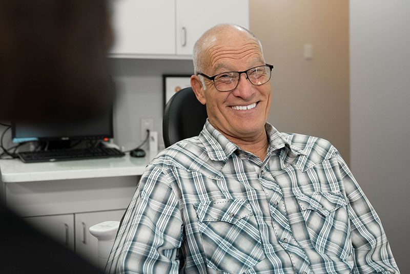 patient smiling brightly while discussing dental treatment info with doctor