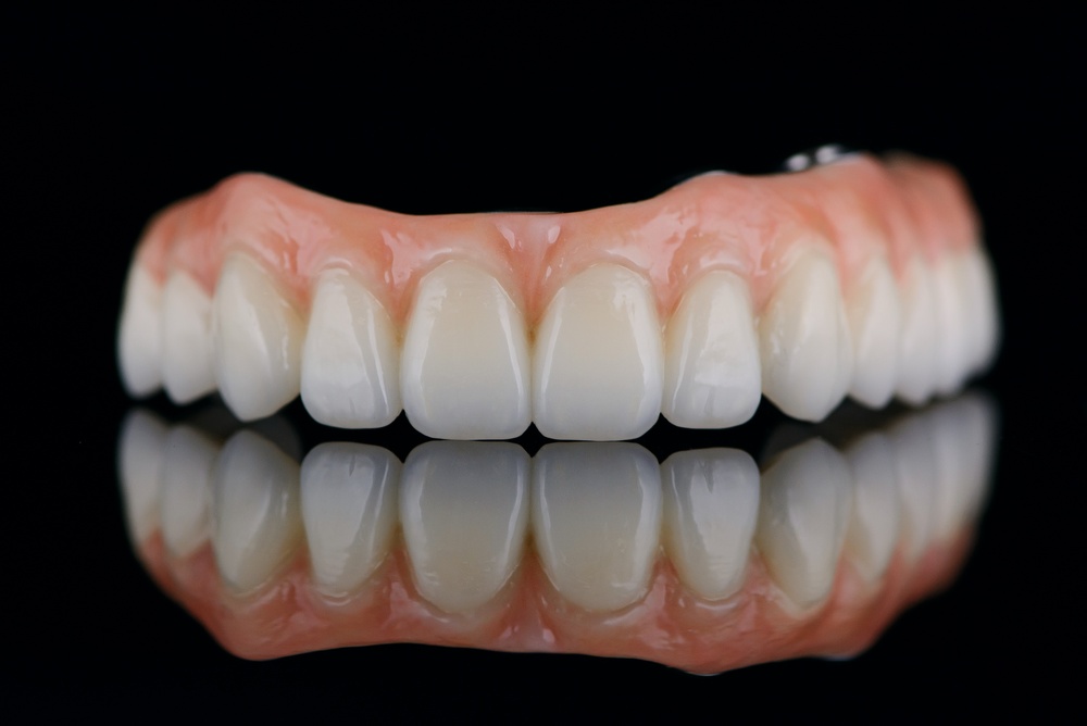 Photo of a dentist smiling, consulting with a patient about dental implants in Jonesboro, AR, with modern dental equipment visible in the background. No text on image.